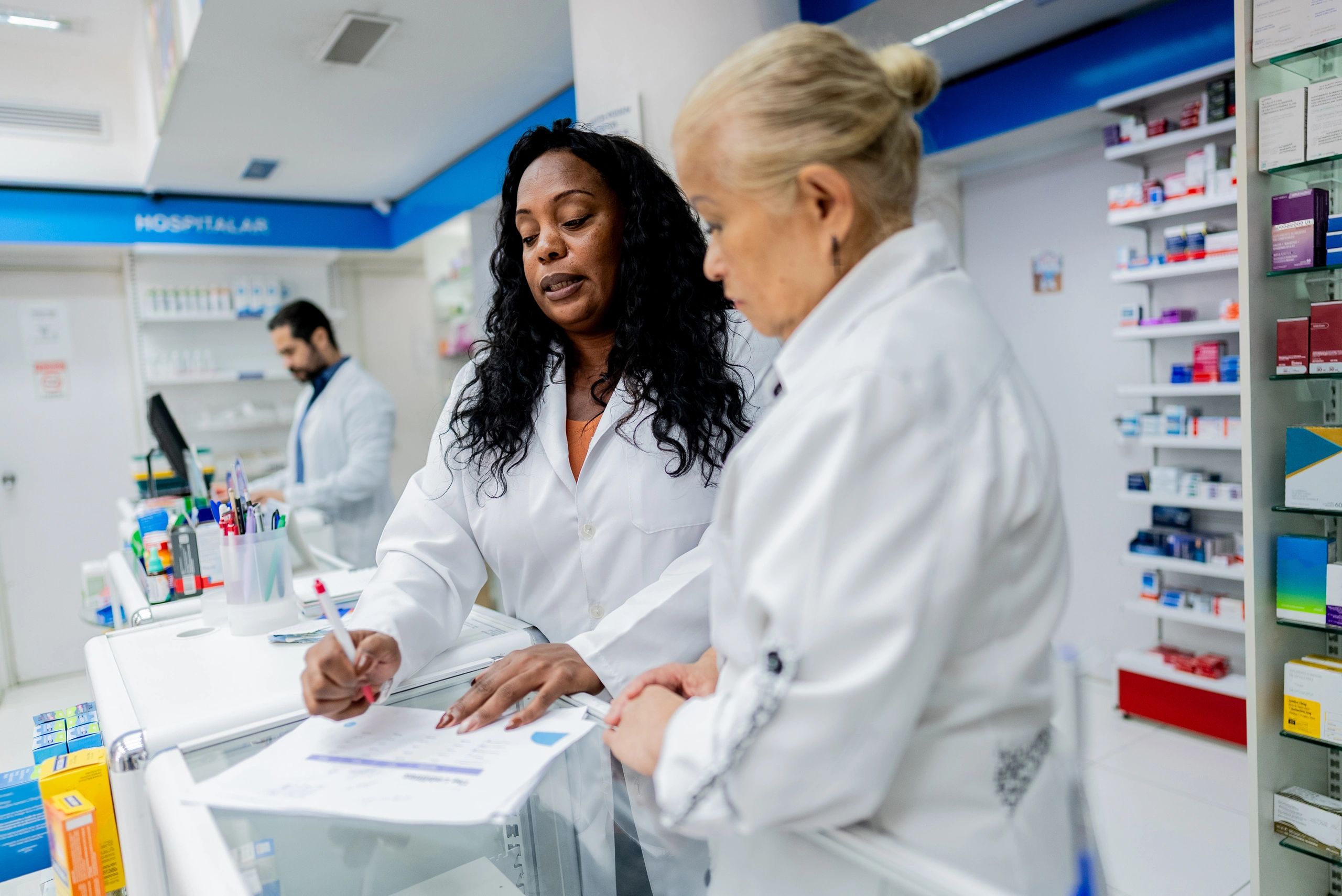 Two pharmacy professionals discussing work at a pharmacy counter